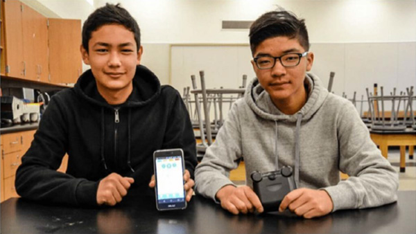 Photo of two students in a classroom, showing their air qualtiy measurements on their phone
