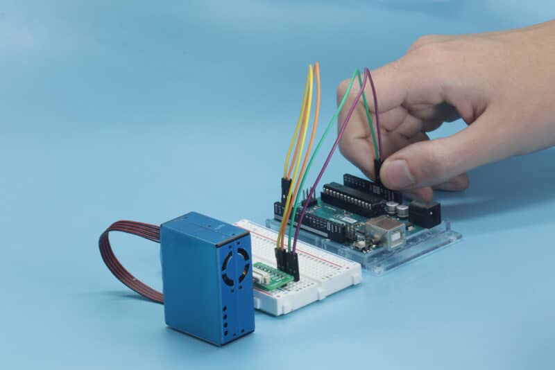 Photo of an assembled Sensor Build Kit, with a student hand plugging in the last two jumper wires.