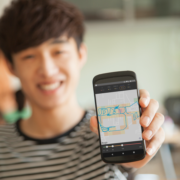 Photo of smiling student showing his phone screen, which displays the app with map of air quality measurements.