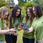 Photo of four students holding AQ-go sensors and phones.