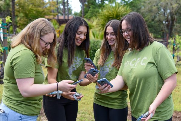 Photo of four students holding AQ-go sensors and phones.